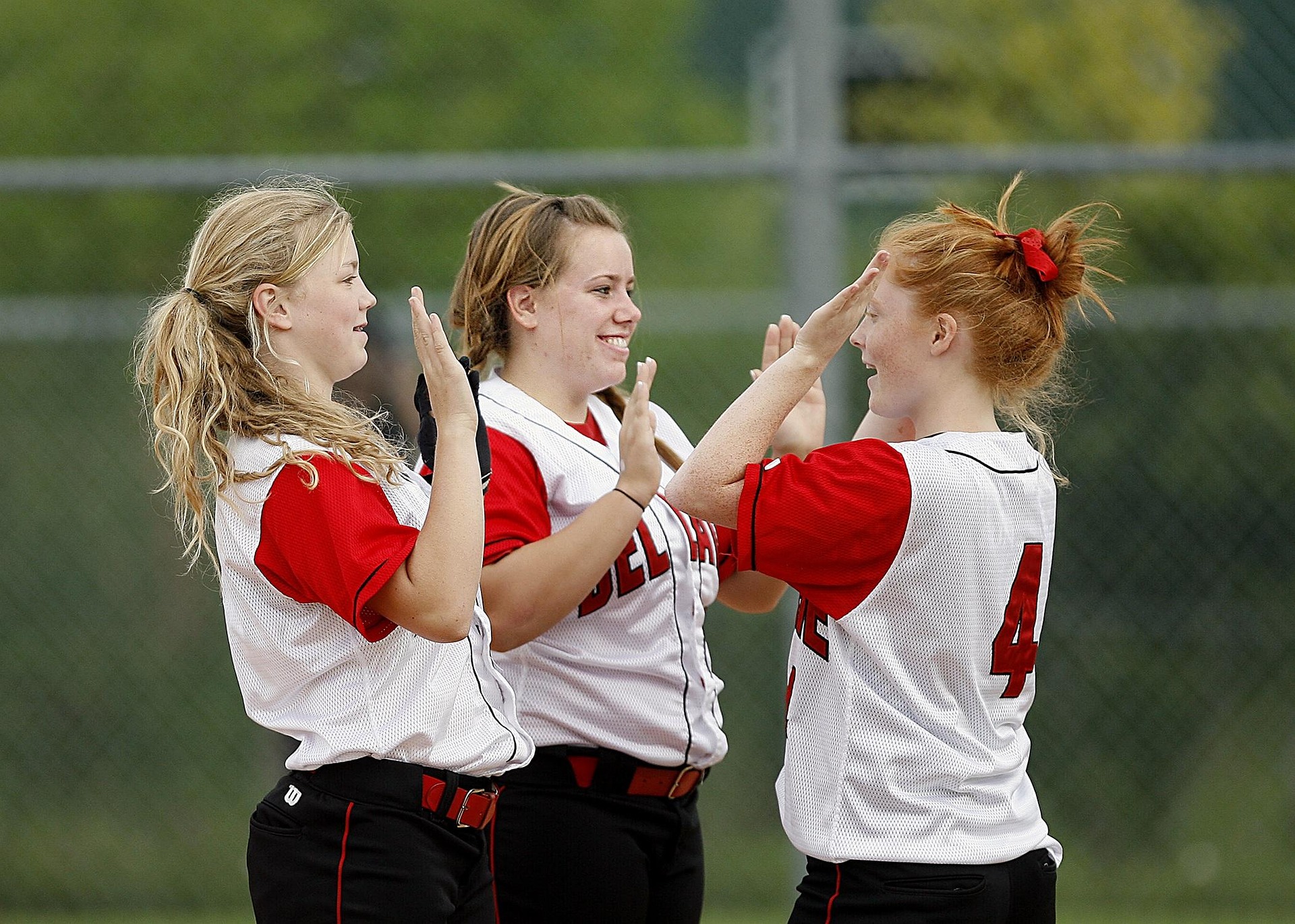 Three girls celebrating in softball uniforms